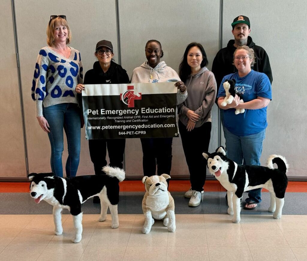 Group of six people posing with dog mannequins at an education center.